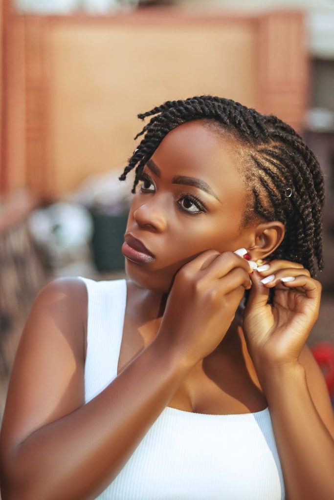 pexels-photo-30091518-1 A stylish young woman adjusting her earrings with focus, captured in natural light.