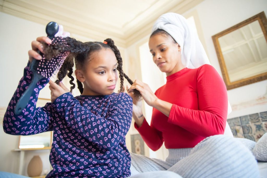 pexels-photo-6948124-1 A mother braids her daughter's hair at home, emphasizing bonding and ethnic hair care.