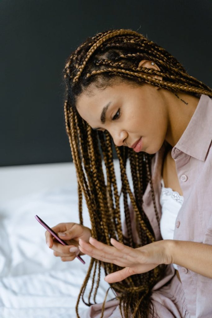 pexels-photo-7607808-1 A focused young woman with braided hair files her nails indoors, showcasing a relaxed and personal grooming moment.